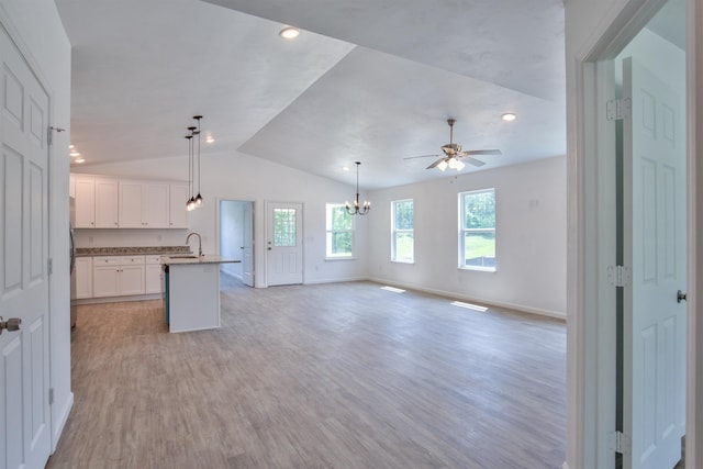 kitchen featuring vaulted ceiling, an island with sink, white cabinetry, hanging light fixtures, and light hardwood / wood-style floors