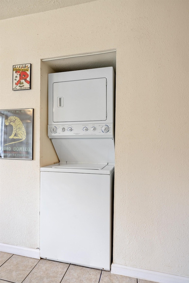 laundry area with stacked washer and dryer and light tile patterned floors