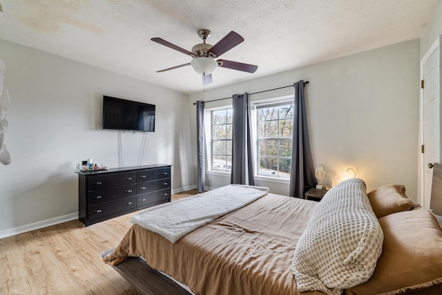 bedroom with ceiling fan, wood-type flooring, and a textured ceiling