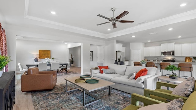 living room with crown molding, wood-type flooring, and a raised ceiling