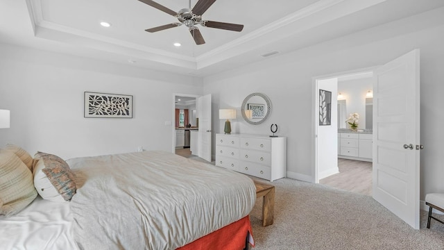 carpeted bedroom with ceiling fan, ensuite bathroom, a raised ceiling, and ornamental molding