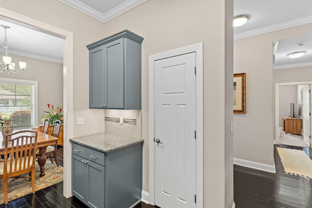 kitchen with light stone counters, a chandelier, gray cabinetry, dark hardwood / wood-style flooring, and ornamental molding