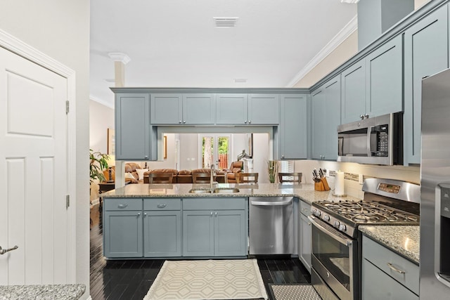 kitchen with sink, light stone counters, kitchen peninsula, crown molding, and appliances with stainless steel finishes