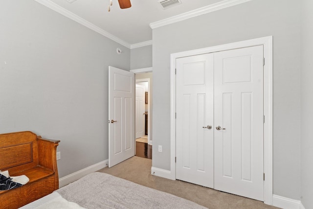 bedroom featuring ornamental molding, light colored carpet, ceiling fan, and a closet