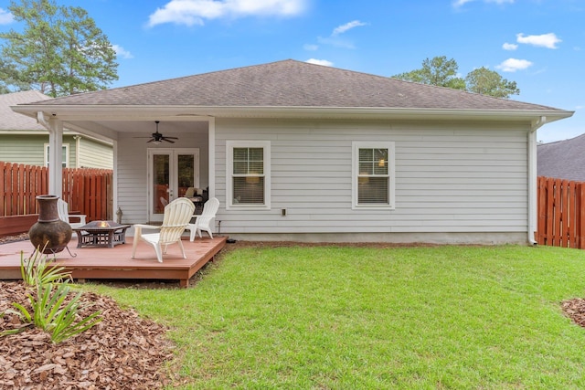 rear view of house featuring ceiling fan, a yard, a wooden deck, and an outdoor fire pit