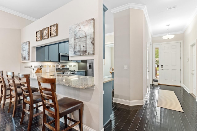 kitchen with stainless steel appliances, kitchen peninsula, dark hardwood / wood-style flooring, a kitchen bar, and blue cabinets