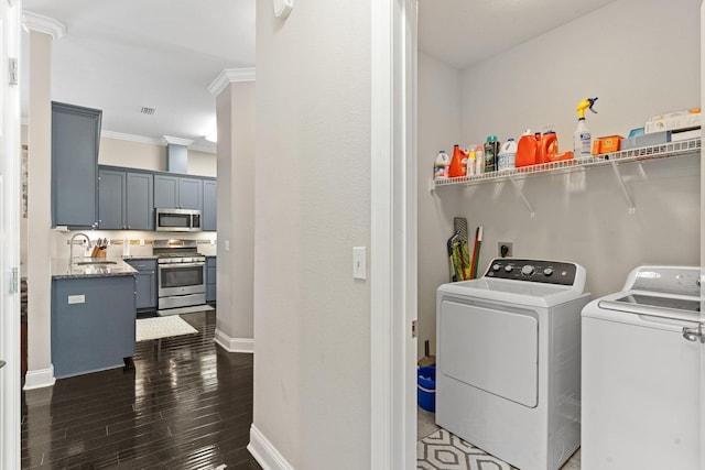 washroom with ornamental molding, washer and clothes dryer, and sink