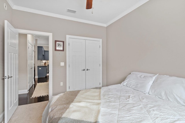 carpeted bedroom featuring a closet, ceiling fan, and ornamental molding