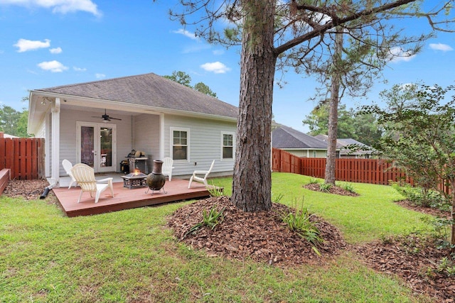 rear view of property with ceiling fan, a yard, a fire pit, and a wooden deck