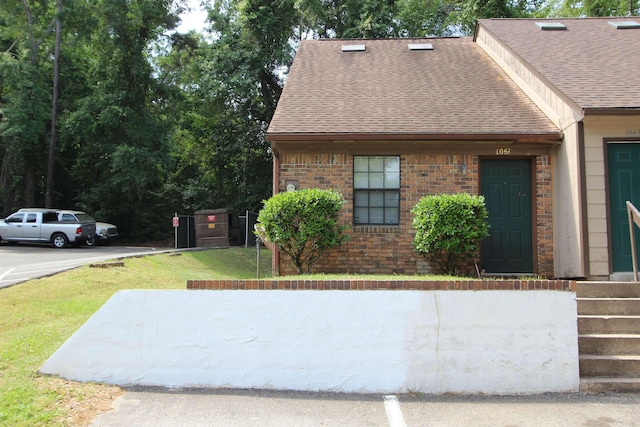 1061 Ocala Rd, Tallahassee, FL 32304 - view of home's exterior featuring a lawn, a shingled roof, and brick siding
