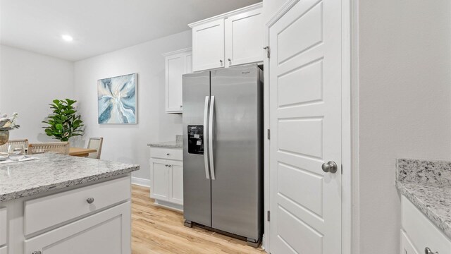 kitchen featuring white cabinets, stainless steel refrigerator with ice dispenser, light hardwood / wood-style flooring, and light stone countertops