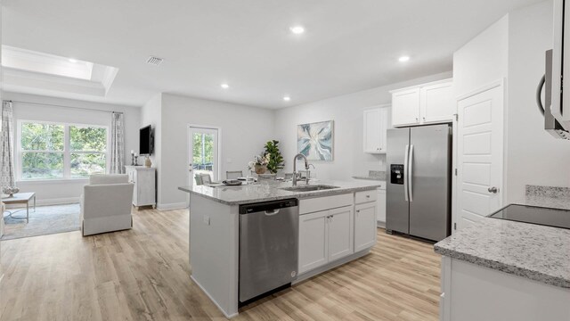 kitchen featuring a center island with sink, stainless steel appliances, sink, light hardwood / wood-style floors, and white cabinets