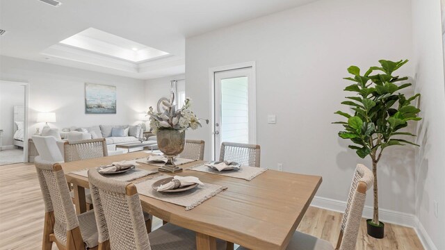 dining area featuring a tray ceiling and light hardwood / wood-style floors