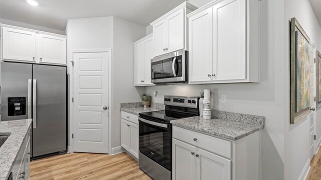 kitchen featuring stainless steel appliances, light hardwood / wood-style floors, white cabinets, and light stone counters