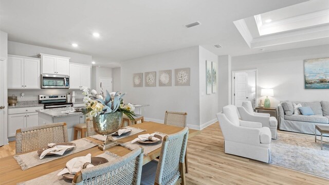 dining area featuring light hardwood / wood-style floors and a skylight