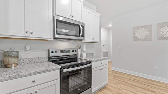 kitchen featuring white cabinetry, appliances with stainless steel finishes, light stone counters, and light hardwood / wood-style floors