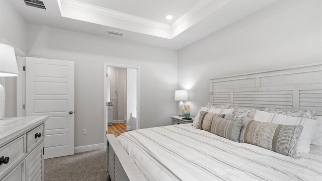 carpeted bedroom with a tray ceiling and ornamental molding