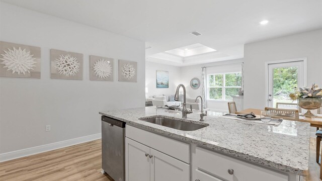 kitchen featuring light hardwood / wood-style floors, sink, light stone counters, stainless steel dishwasher, and white cabinets