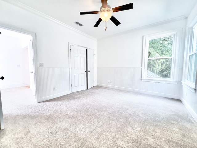 carpeted spare room featuring crown molding and ceiling fan