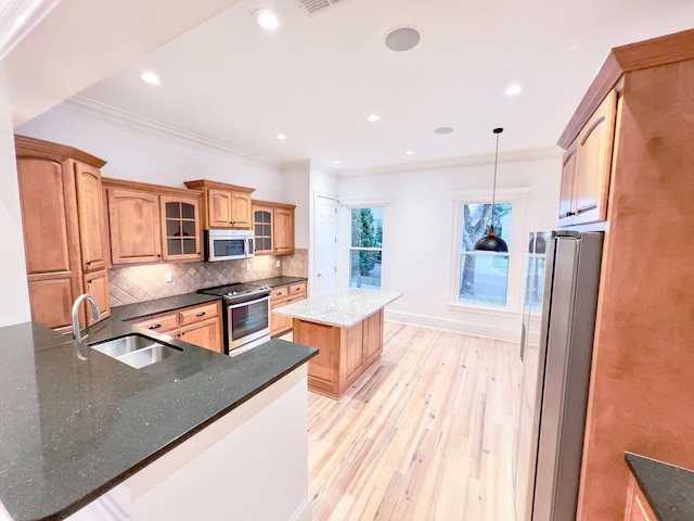 kitchen with a kitchen island, appliances with stainless steel finishes, pendant lighting, tasteful backsplash, and sink