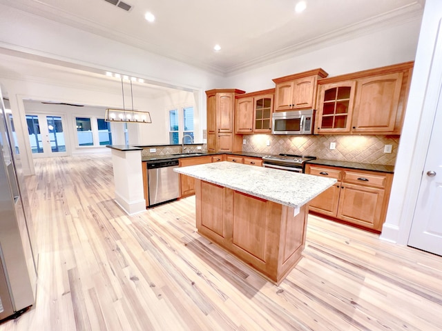 kitchen featuring pendant lighting, sink, kitchen peninsula, stainless steel appliances, and light hardwood / wood-style flooring