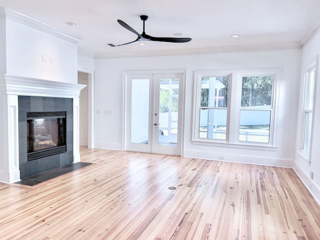 unfurnished living room featuring a tile fireplace, ornamental molding, ceiling fan, and light hardwood / wood-style floors