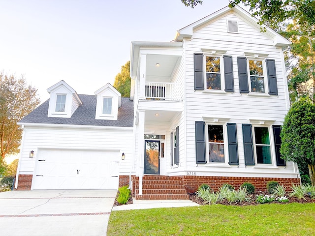 view of front of property featuring a balcony, a garage, and a front lawn