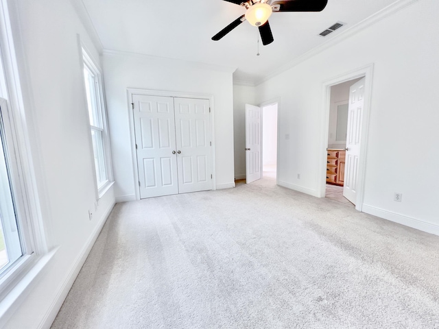 unfurnished bedroom featuring crown molding, light colored carpet, ceiling fan, and a closet