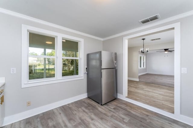 181 E Center St, Perry, FL 32348 - kitchen with freestanding refrigerator, wood finished floors, a chandelier, ornamental molding, and pendant lighting