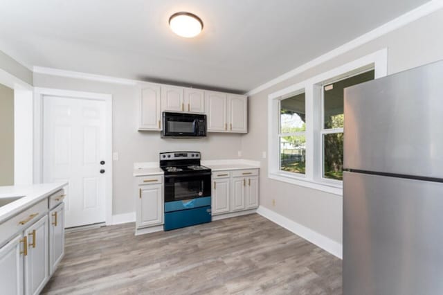 181 E Center St, Perry, FL 32348 - kitchen featuring black appliances, light countertops, light wood-style flooring, and white cabinets