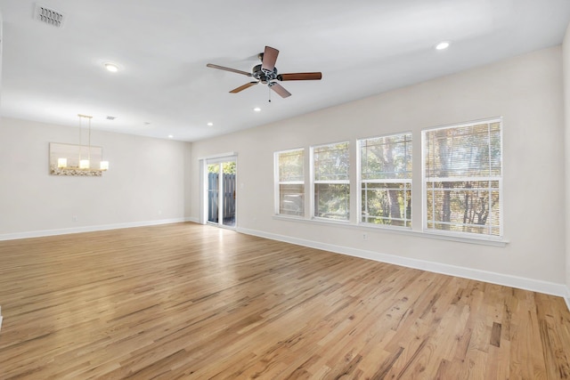 unfurnished living room with ceiling fan with notable chandelier and light wood-type flooring