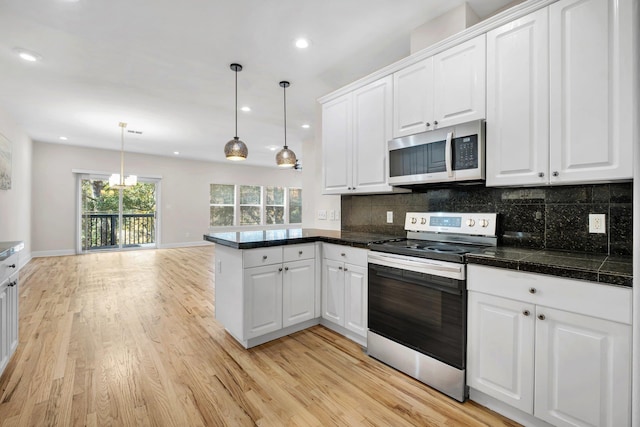 kitchen featuring white cabinetry, stainless steel appliances, and hanging light fixtures