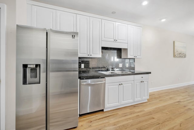 kitchen with sink, stainless steel appliances, light hardwood / wood-style floors, decorative backsplash, and white cabinets