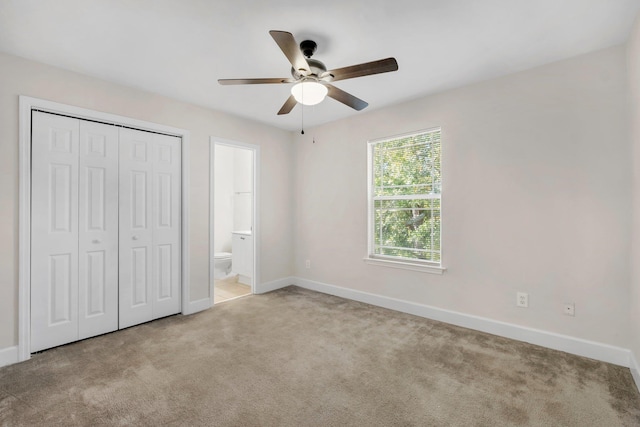 unfurnished bedroom featuring light carpet, a closet, ensuite bath, and ceiling fan