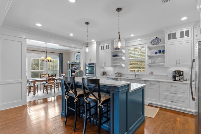 kitchen featuring pendant lighting, sink, appliances with stainless steel finishes, a center island, and white cabinets