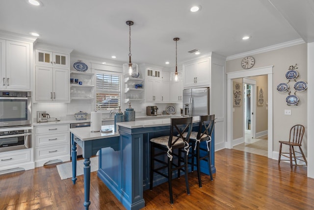 kitchen with white cabinetry, stainless steel appliances, a kitchen island, and pendant lighting