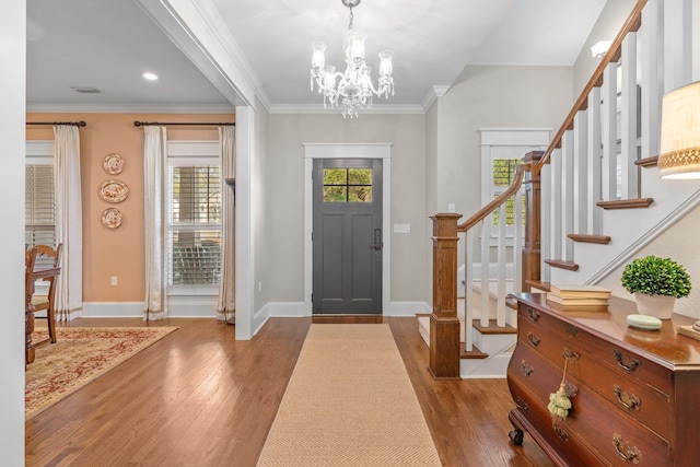 foyer with hardwood / wood-style flooring, crown molding, and a chandelier