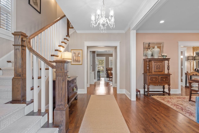 entryway with an inviting chandelier, ornamental molding, and dark hardwood / wood-style floors