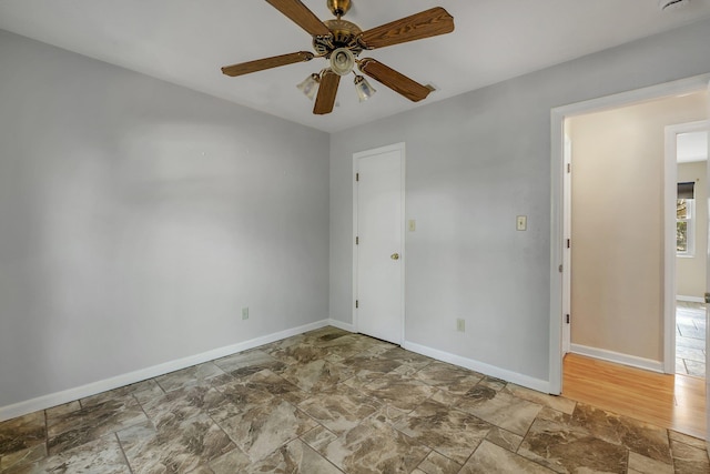 spare room with stone finish floor, baseboards, and a ceiling fan