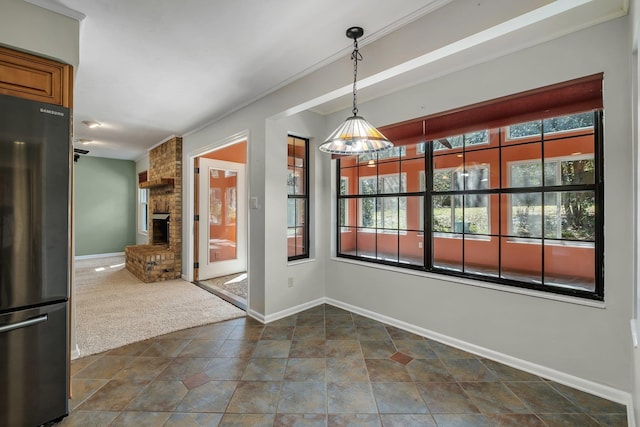 unfurnished dining area with dark colored carpet, a fireplace, and baseboards