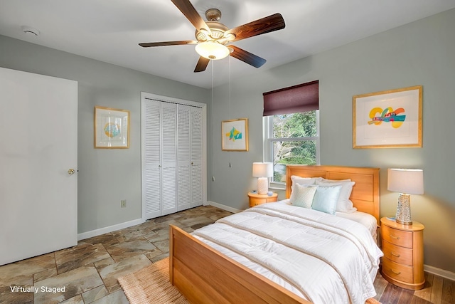 bedroom featuring a closet, stone finish floor, baseboards, and ceiling fan