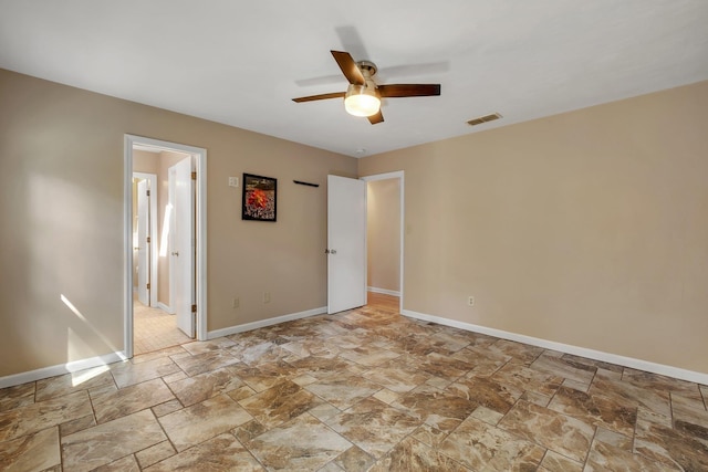 spare room with ceiling fan, stone finish floor, visible vents, and baseboards