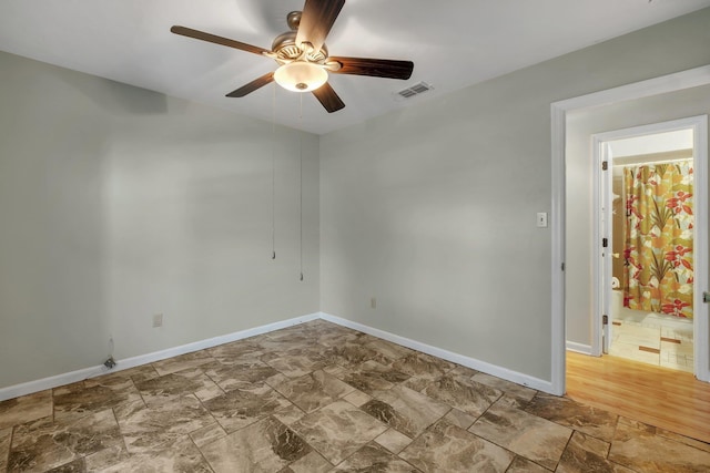 unfurnished room with baseboards, visible vents, a ceiling fan, and stone finish flooring