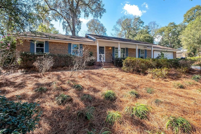 ranch-style house featuring brick siding, a porch, and an attached garage