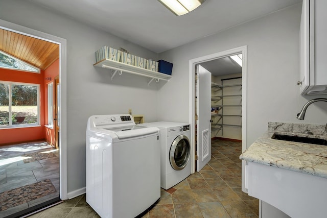 clothes washing area with cabinet space, baseboards, a sink, and washing machine and clothes dryer