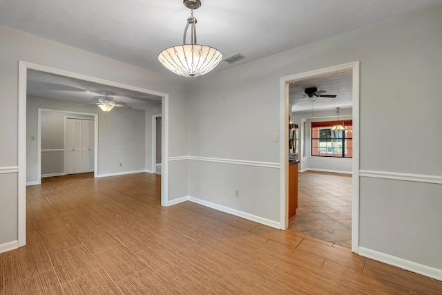 empty room with visible vents, light wood finished floors, and baseboards