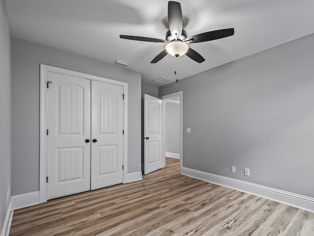 unfurnished bedroom featuring ceiling fan, light hardwood / wood-style floors, and a closet