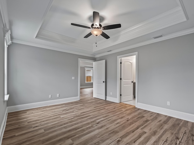 unfurnished bedroom with hardwood / wood-style floors, crown molding, a raised ceiling, and ceiling fan