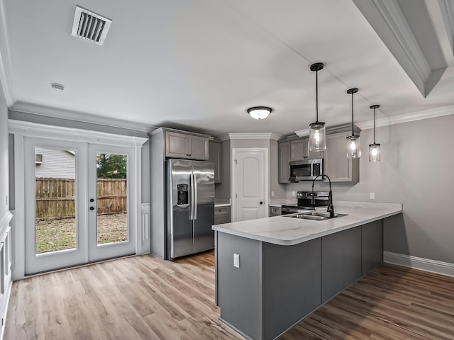 kitchen with pendant lighting, sink, appliances with stainless steel finishes, ornamental molding, and kitchen peninsula