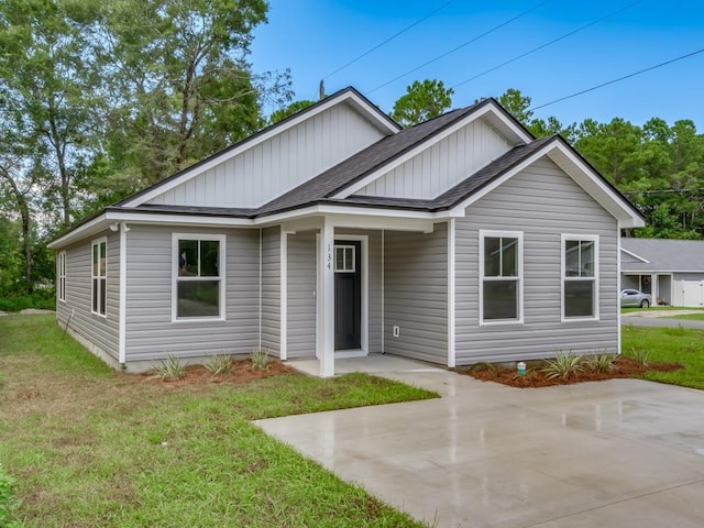 67 Broken Bow Trl, Crawfordville, FL 32327 - view of front of house with a patio area, roof with shingles, a front yard, and board and batten siding
